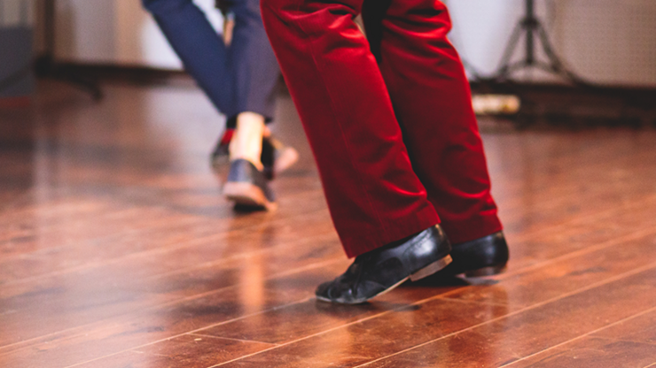 Ein Holzboden auf dem Beine und Füße von mehreren Personen sichtbar sind die tanzen.