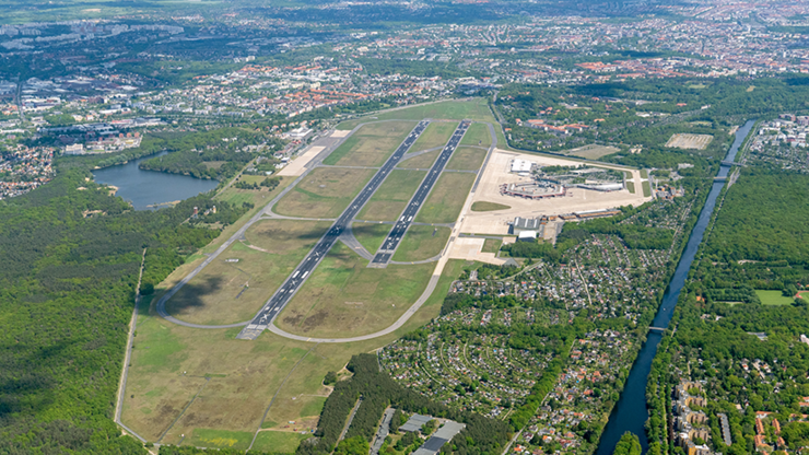 Luftbild vom ehemaligen Flughafen Tegel mit der gut sichtbaren Landebahn und den Terminalgebäuden. Rund herum sieht man Berlin.