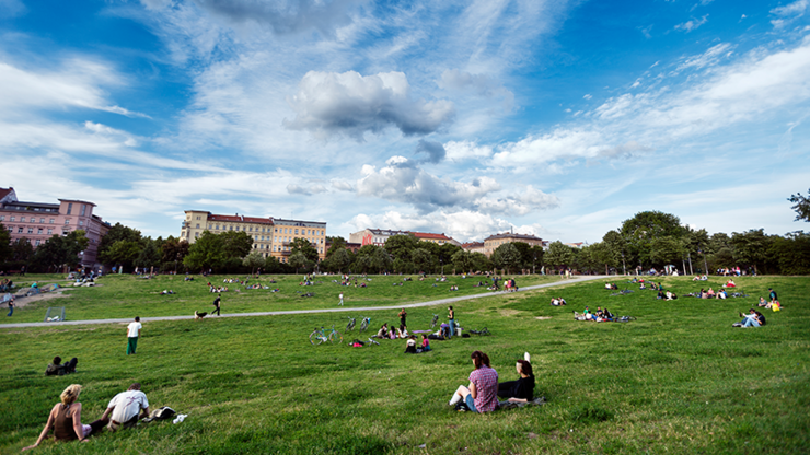 Der Görlitzer Park in Berlin, junge Leute sitzen verteilt im Park, im Hintergrund stehen Wohnhäuser.